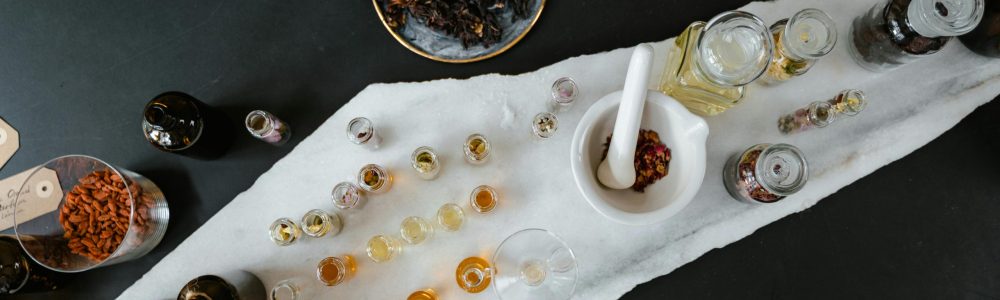 Overhead view of an aromatherapy setup with glass bottles and ingredients on a table.