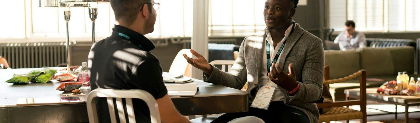 Two men having a casual discussion in a bright indoor setting, highlighting mentorship.